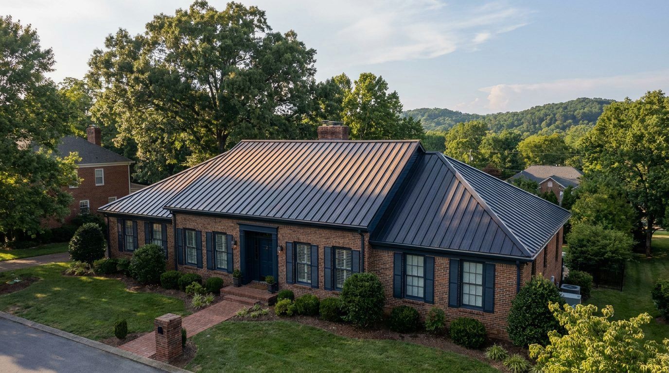 Dark standing seam metal roof on a Tennessee brick house among oak trees